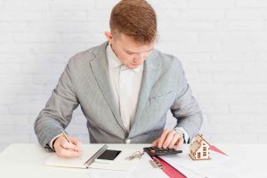 Real estate investor calculating interest rate on owner financing using calculator and documents.