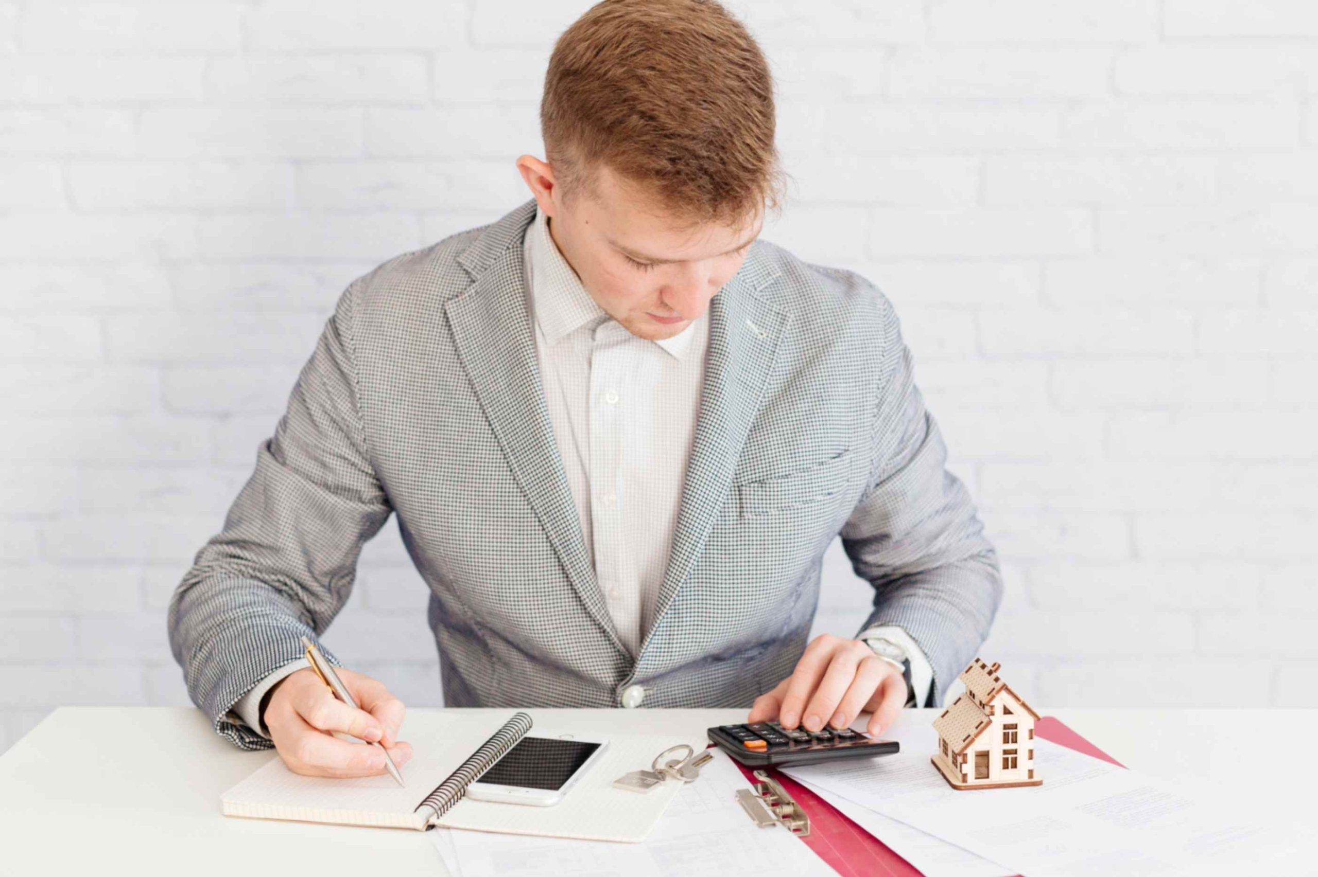 Real estate investor calculating interest rate on owner financing using calculator and documents.