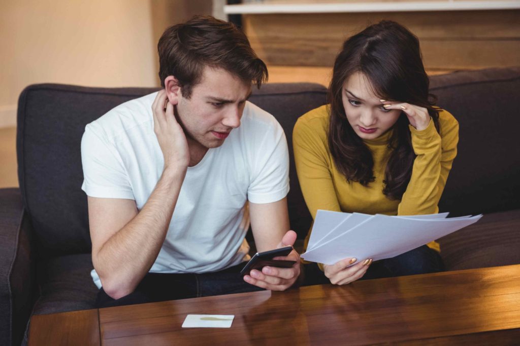 Stressed couple reviewing financial paperwork and credit information, illustrating the concept of Private Credit vs Private Debt