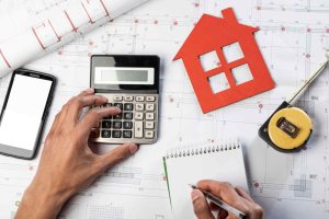 Calculating commercial property mortgage payments with calculator, blueprint, and planning tools