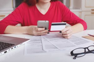Person reviewing credit card statement and legal documents while preparing a sample answer to summons for credit card debt at home.