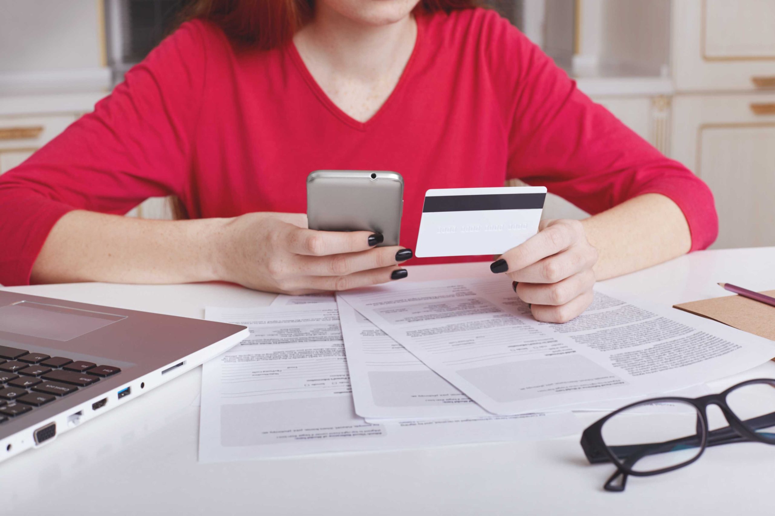 Person reviewing credit card statement and legal documents while preparing a sample answer to summons for credit card debt at home.