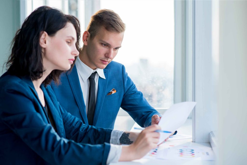 Two professionals analyzing economic data charts related to expansionary and contractionary fiscal policy in a modern office setting