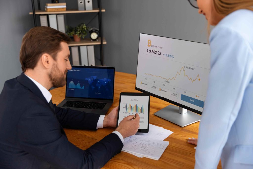 Two professionals analyzing financial data and credit statistics on digital screens, including Bitcoin price trends and loan performance charts.