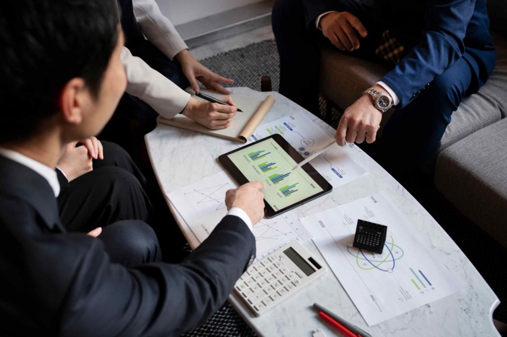 Business professionals analyzing financial charts on a tablet, discussing portfolio investment strategies and performance metrics