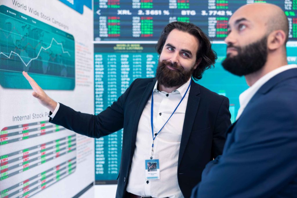 Financial analyst explaining XRP ETF market trends to investor on digital stock chart display